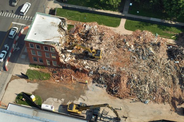 Demolition of Historic Edwards Building in Berea, Kentucky. Crawler excavator demolishing brick walls of old structure.