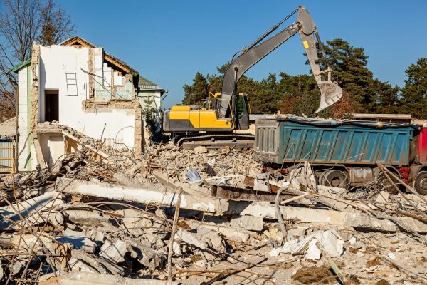 The excavator loads the remains of the destroyed building in the car
